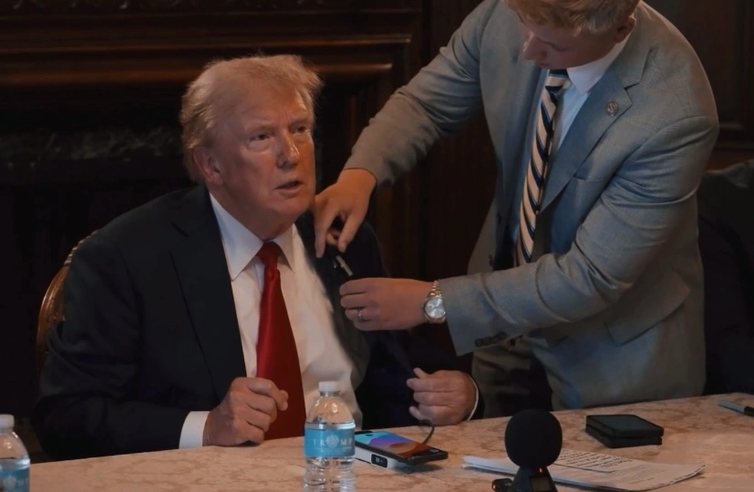 John Jennings holds a microphone up to President Trump on stage.